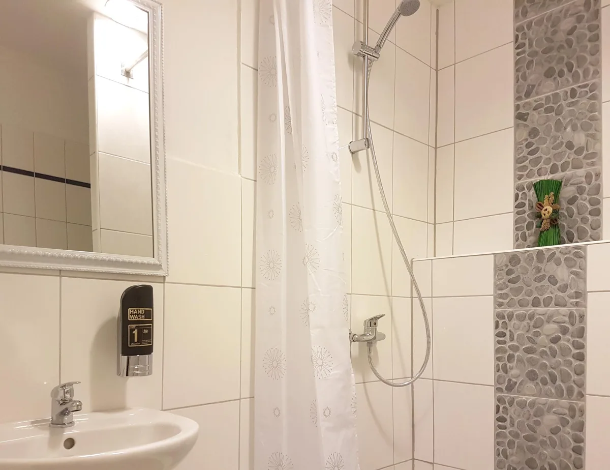 Badezimmer mit Waschbecken, Spiegel und Dusche